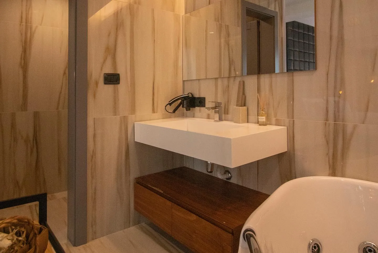Bathroom with marble-effect tiling, a wall-mounted basin on a dark wood vanity and a mirror