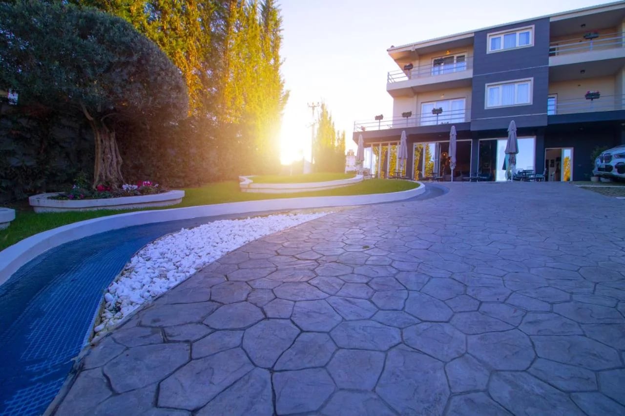 The hotel forecourt at sunset with a tiled water feature, lawn and olive tree