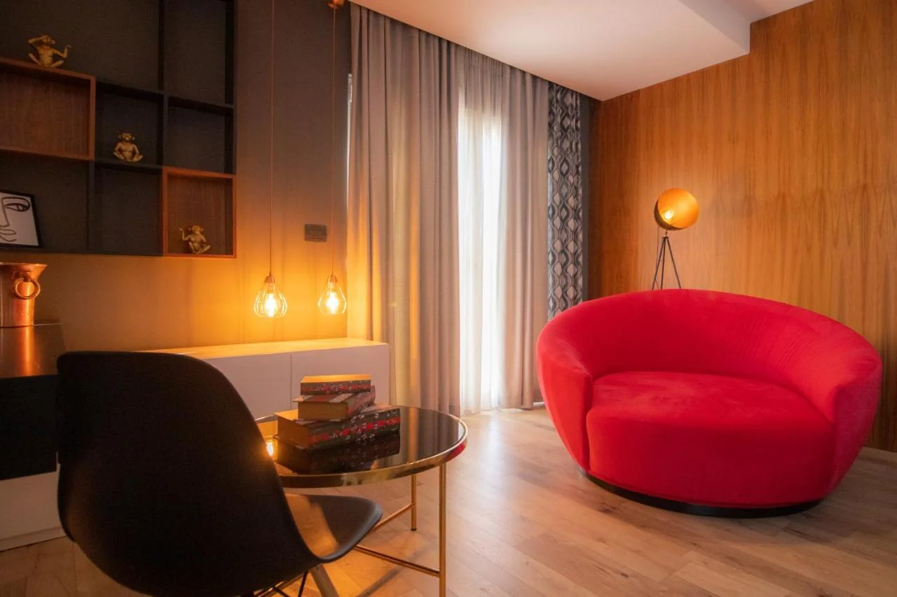 Lounge seating area with a round red velvet sofa, tripod globe lamp and wood-panelled wall