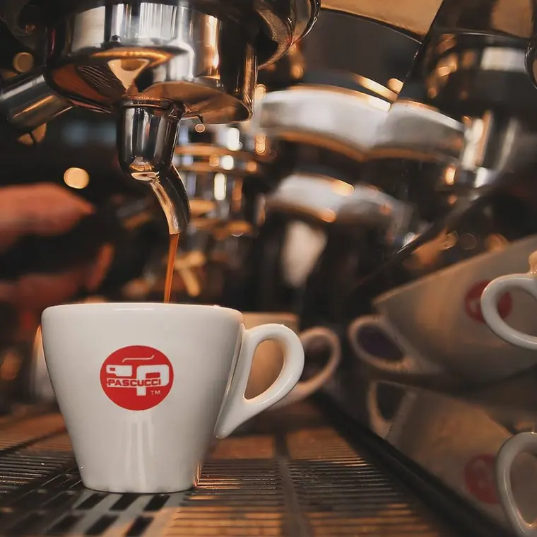Espresso pouring from machine group head into a cup