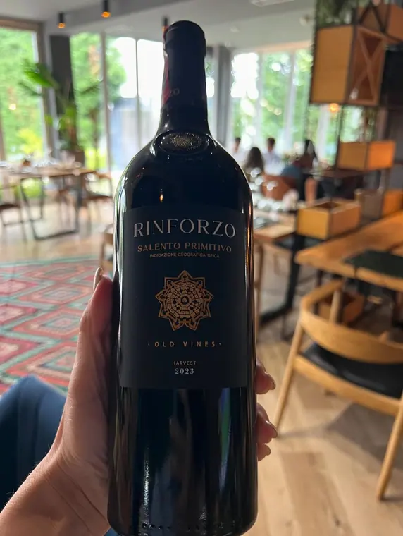 Hand holding a bottle of red wine in the dining room