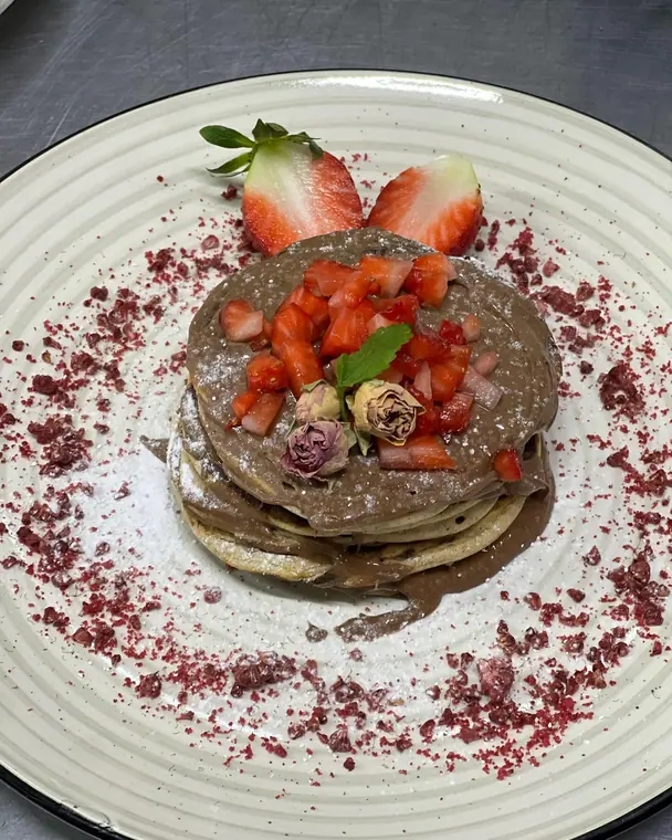 Chocolate pancake stack with strawberries and dried rosebuds