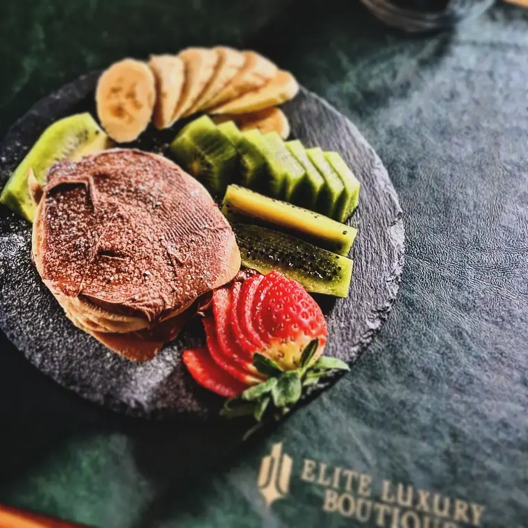 Chocolate pancakes with kiwi, banana and strawberry on a slate disc