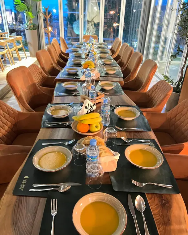 Long table lined with orange chairs and bowls of soup