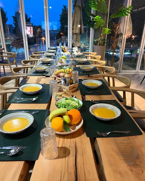 Long table with soup bowls and fruit plates, blue evening windows