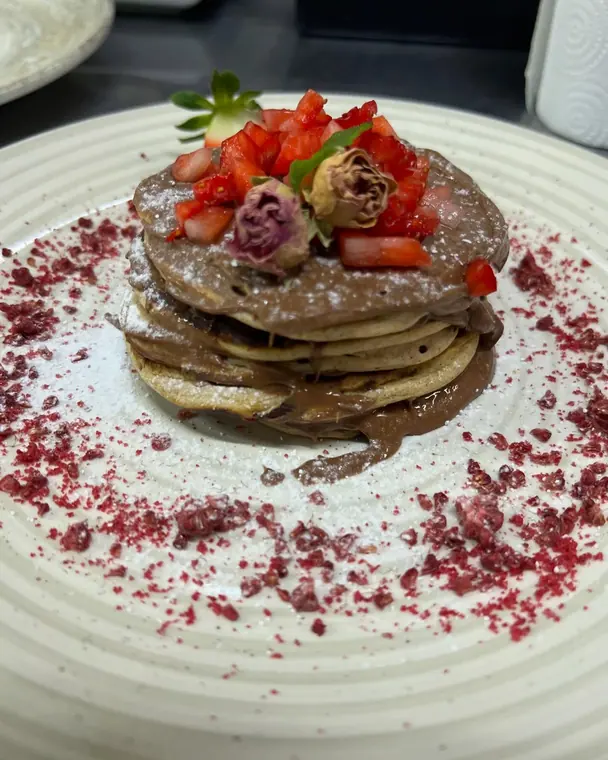 Pancake stack with chocolate spread, strawberries and dried roses