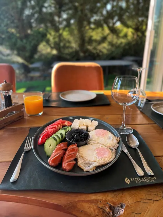 Plate of fried eggs, sausages, cheese, tomato and olives by window
