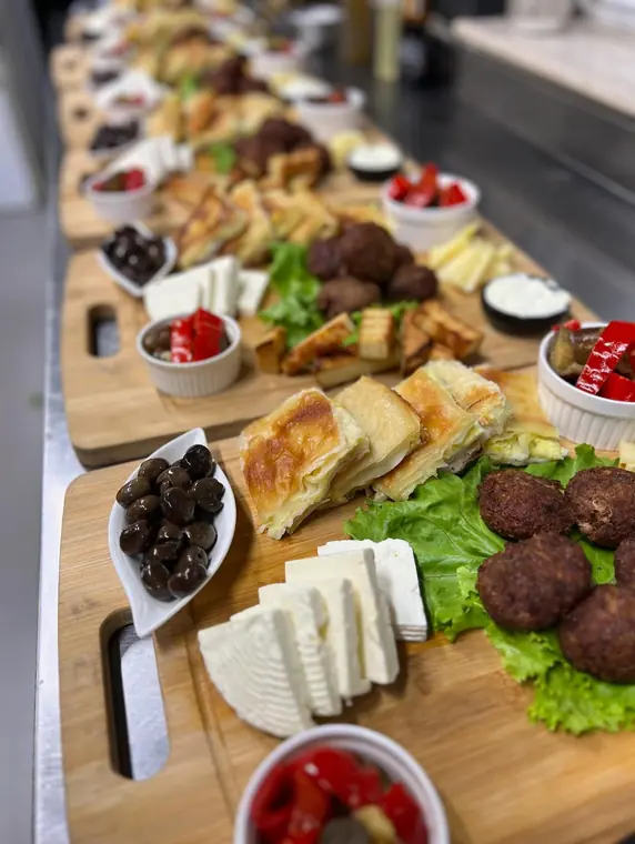 Row of breakfast boards with cheese, olives, byrek and meatballs