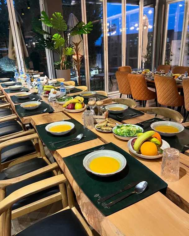 Set table beside glass wall at dusk with soup, salad and fruit