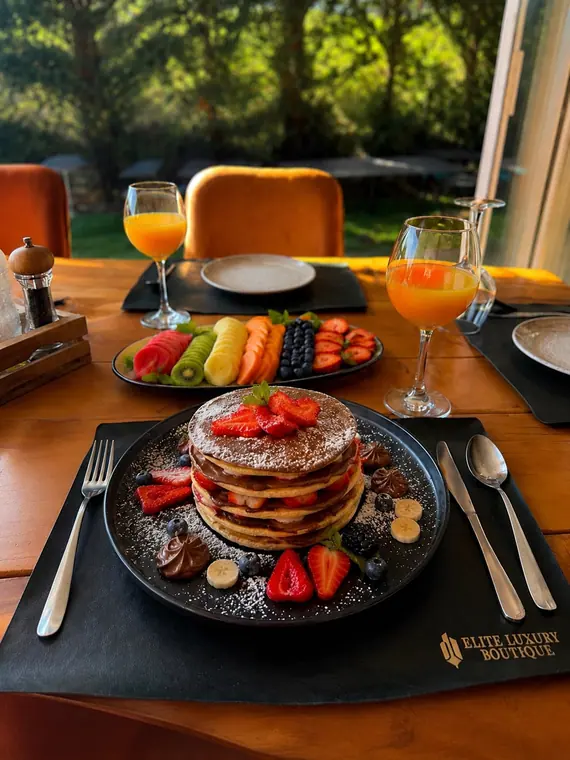 Stacked pancakes with strawberries and fruit platter on garden-side table