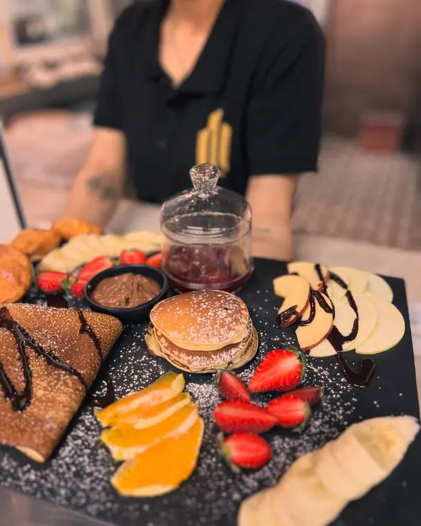 Staff member behind a slate board of pancakes and fruit