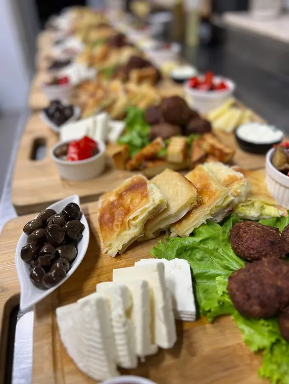 Wooden boards with cheese, olives, byrek, meatballs and peppers