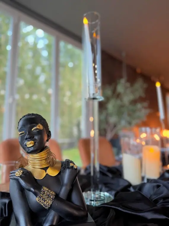 Black and gold figurine on black satin runner with tall candles