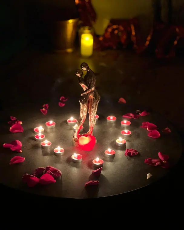 Couple figurine ringed by tealights and rose petals on dark table