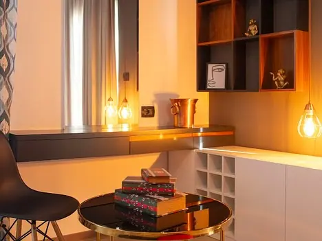 Desk area with pendant bulbs, shelving and gift boxes on round table