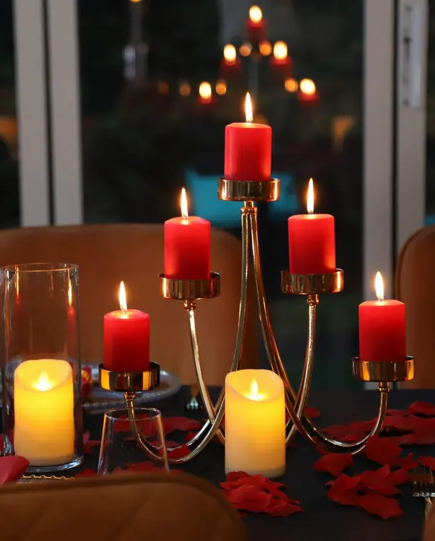 Gold candelabra with red pillar candles and scattered petals on table