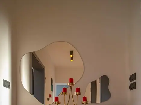 Irregular wall mirror reflecting red candle candelabra