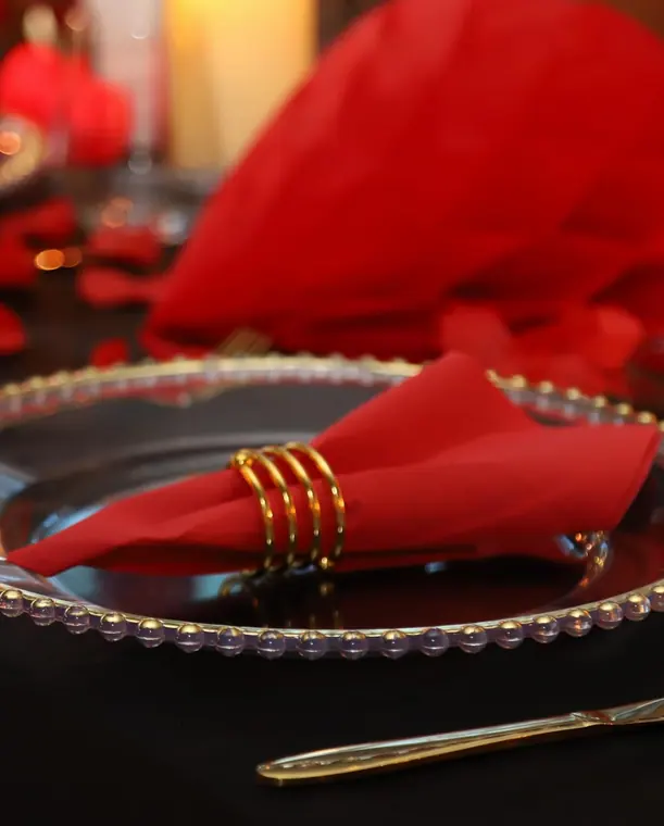 Red napkin in gold ring on beaded charger plate
