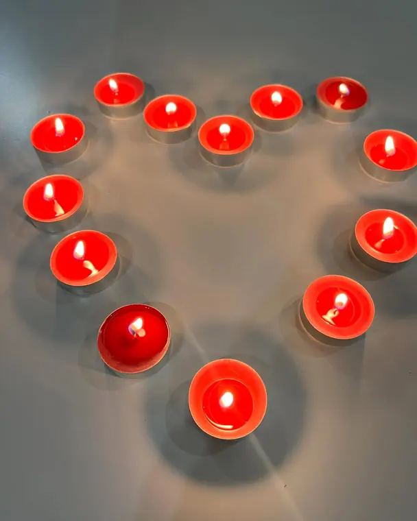 Red tealights arranged in a heart shape on white surface