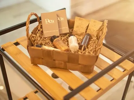 Wicker basket of toiletry sachets and bottles on wooden rack