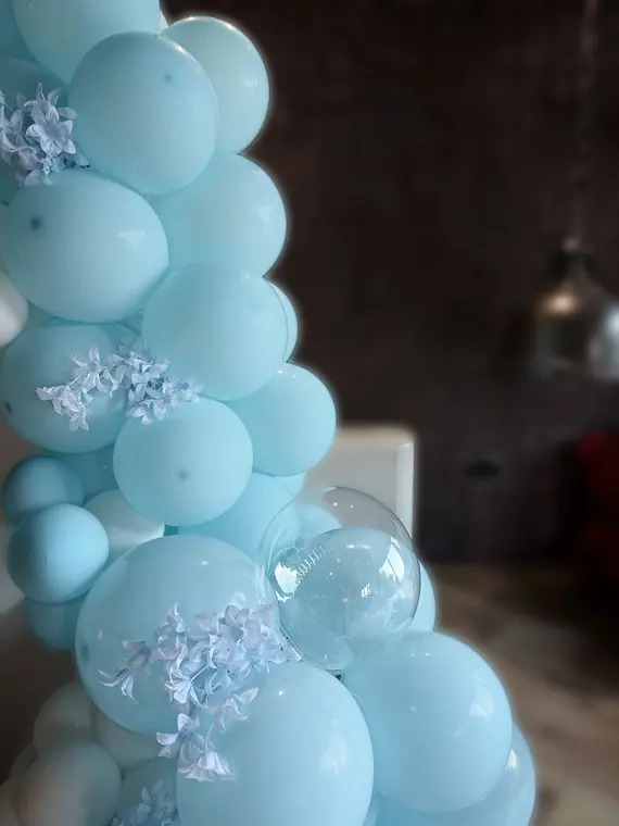 Close view of pale blue balloon garland with white silk flowers