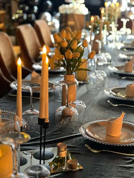 Close view of place settings with orange tulips and taper candles