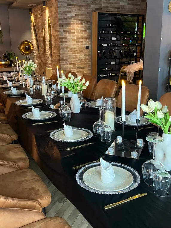 Long dressed table with white tulips and candles, wine rack behind