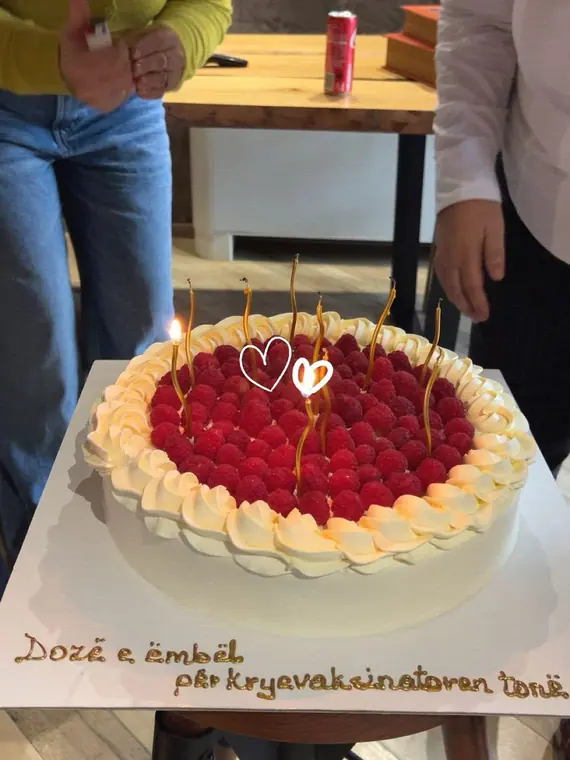 Raspberry cream cake with lit candles held on board