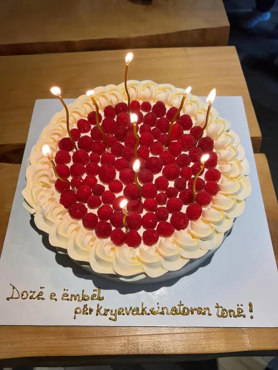 Raspberry cream cake with lit candles on board