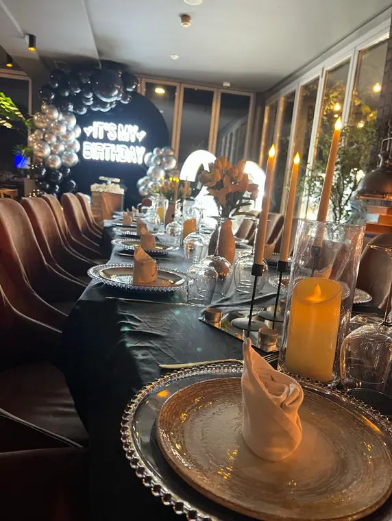 Row of velvet chairs along dressed table toward neon sign