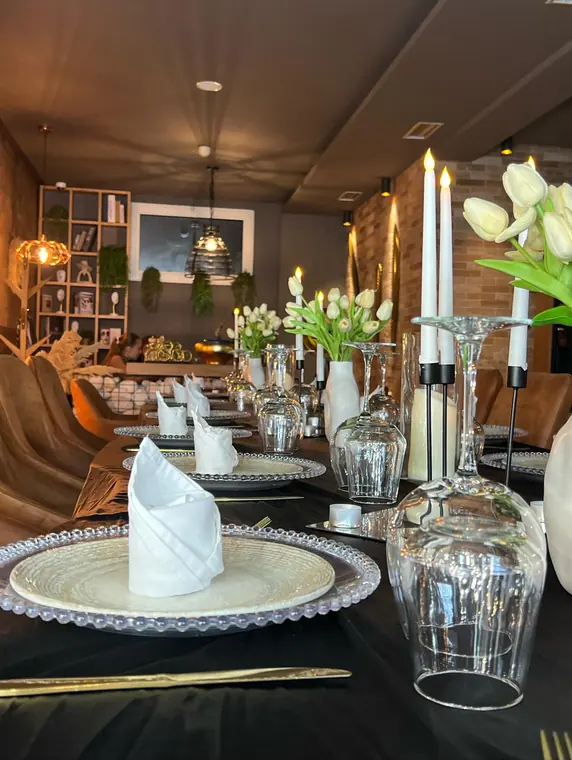 Table set with beaded chargers, folded napkins, tulips and candles