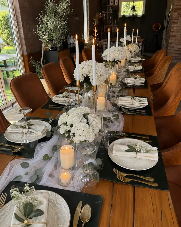 Banquet table with white hydrangeas, candles, gold cutlery and slate mats