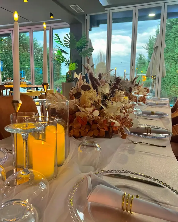 Close view of banquet place settings, candles and dried flowers
