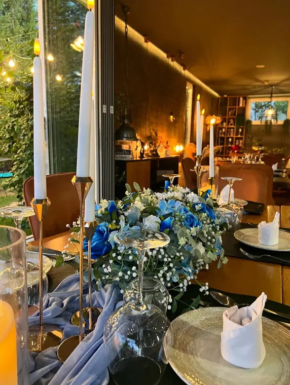 Evening table with blue and white flowers, candles, gauze runner