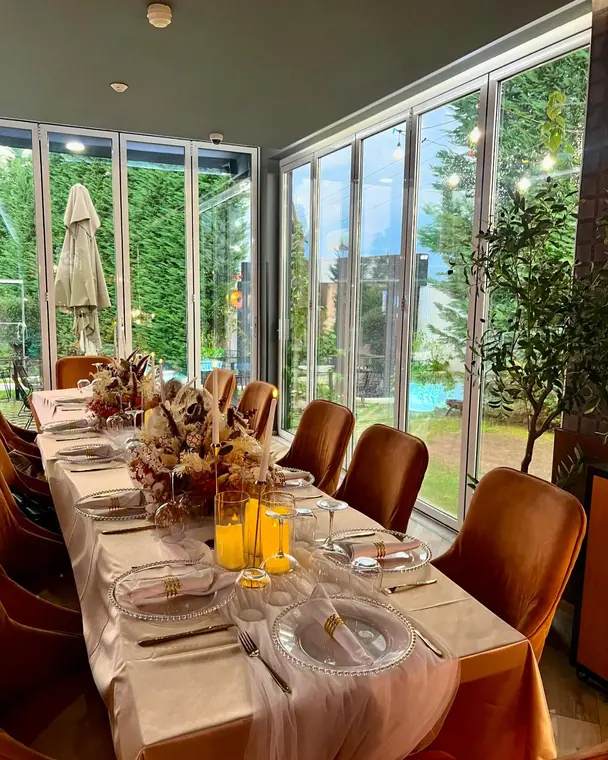 Long dressed table with candles and floral centrepiece by glass wall