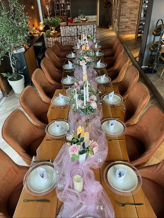 Overhead view of long table with pink tulle runner, roses and candles