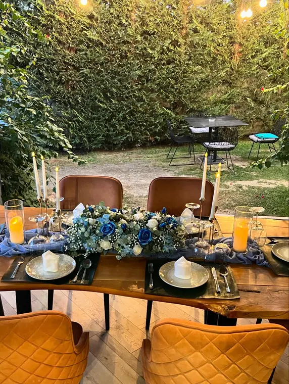 Table set with blue and white rose runner, candles, garden behind