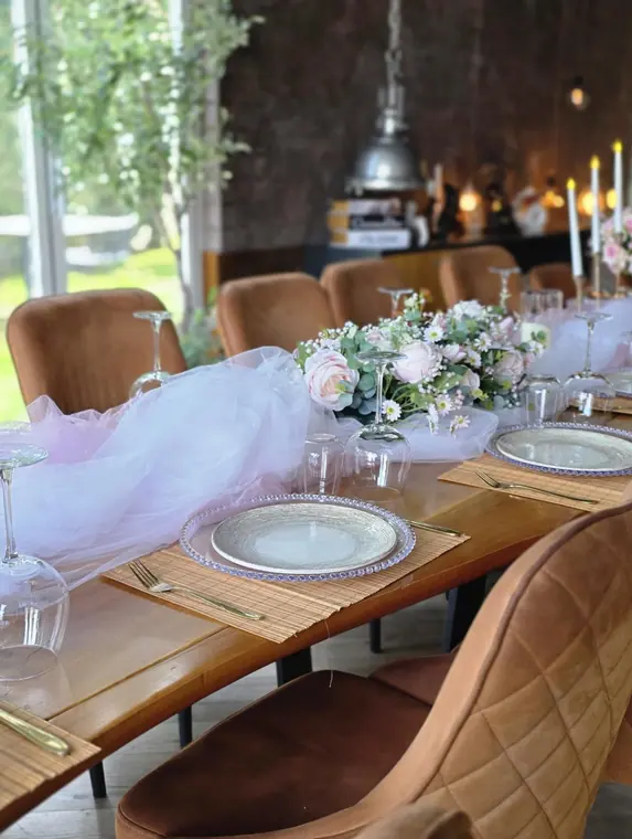 Table with pink tulle runner, rose centrepiece and glass chargers
