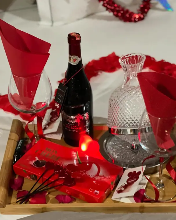Wooden tray with red wine, chocolates, glasses and rose petals