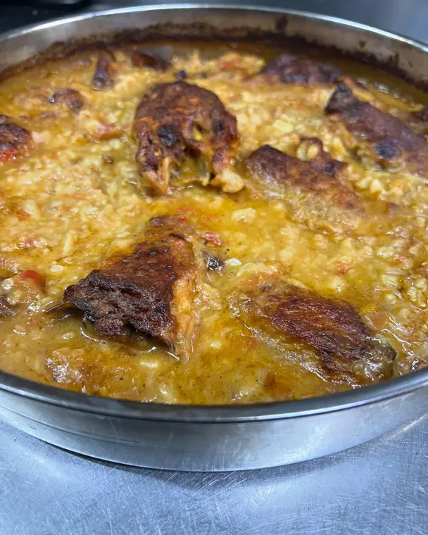 Baked rice with browned meat pieces in a metal tray