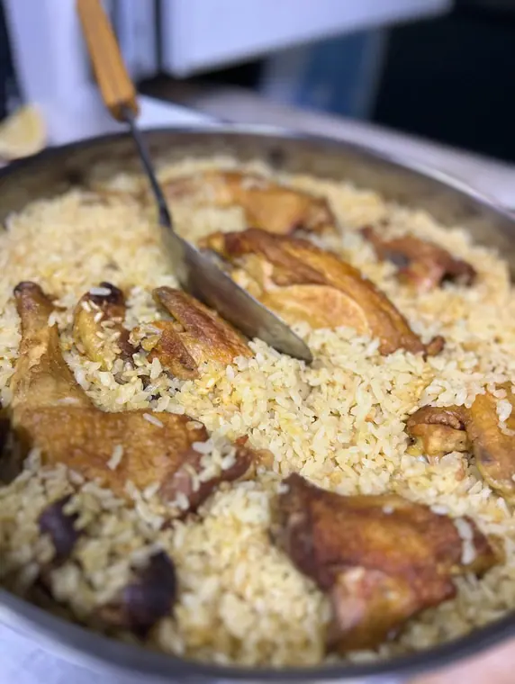 Baked rice with roasted chicken and serving spoon in tray