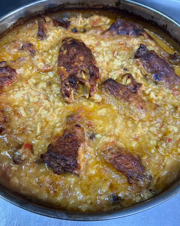 Baked rice with roasted chicken pieces in a metal tray