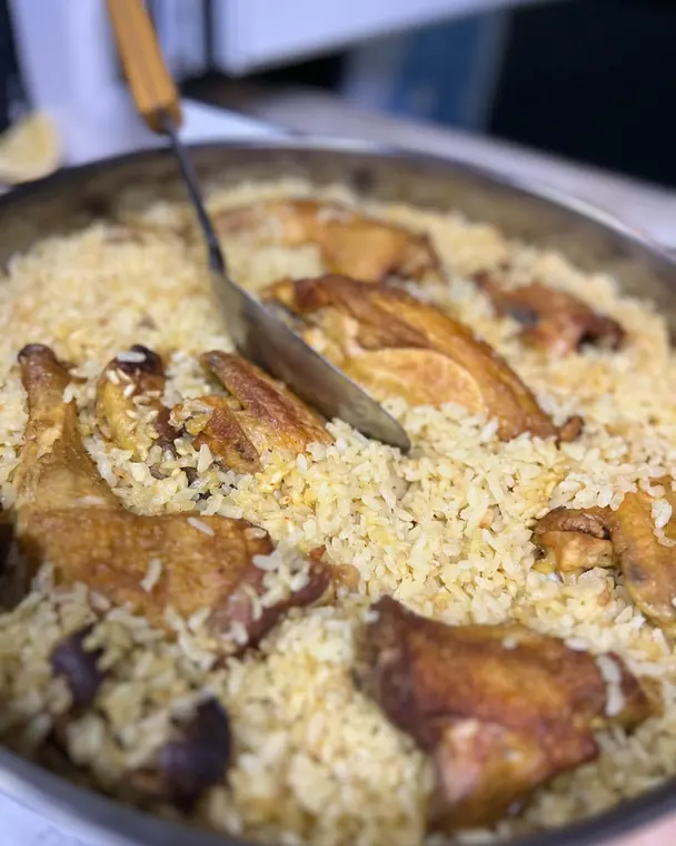 Baked rice with roasted chicken pieces in metal tray