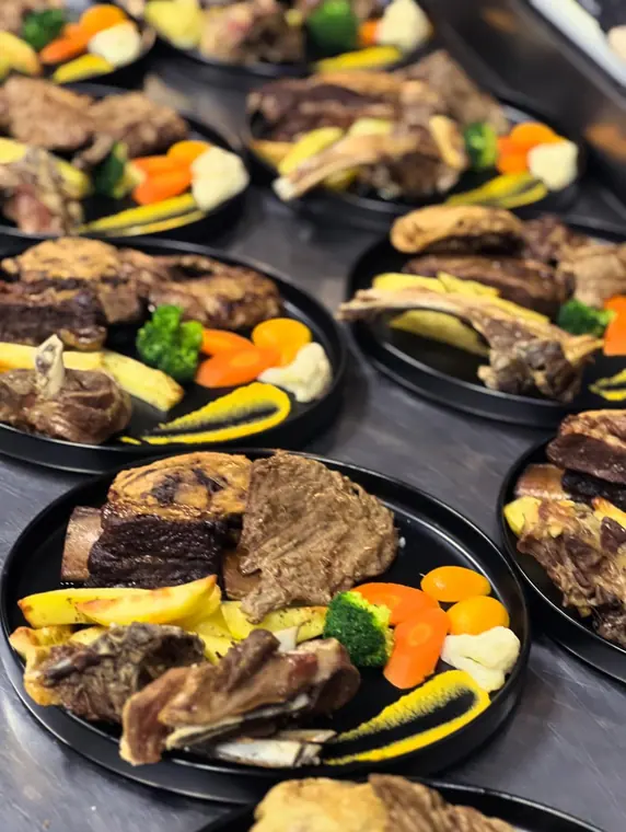 Banquet plates of grilled meat, potatoes and vegetables