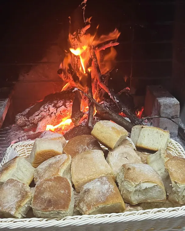 Basket of bread rolls in front of a burning wood fire