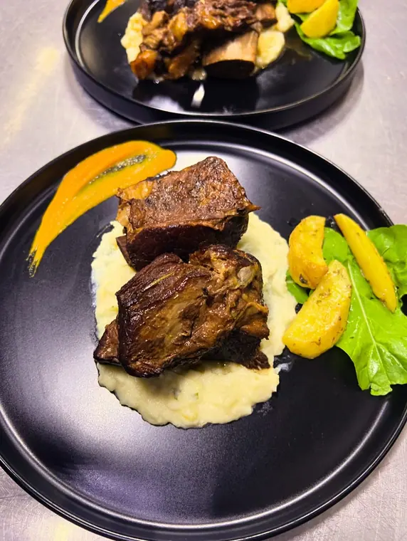 Braised beef on mashed potato with roast potatoes and rocket