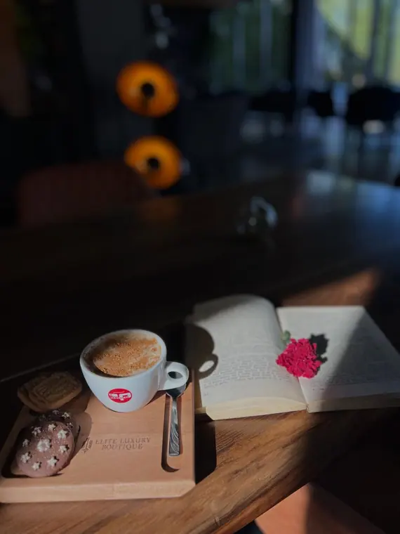 Cappuccino and biscuits on branded wooden board beside open book