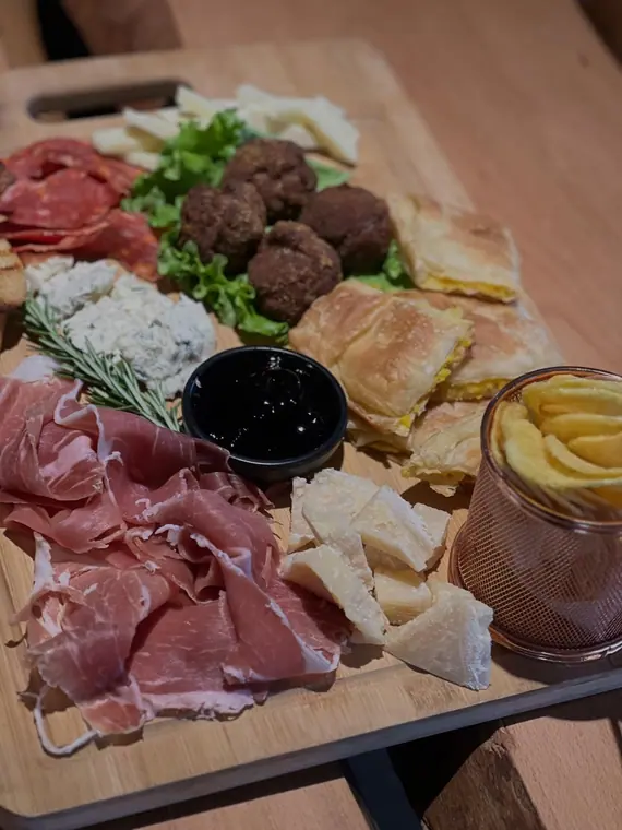 Charcuterie and cheese board with crisps basket on wooden table