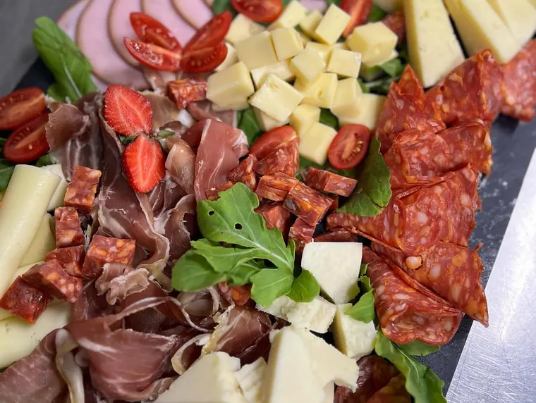 Charcuterie board with salami, prosciutto, cheese and rocket