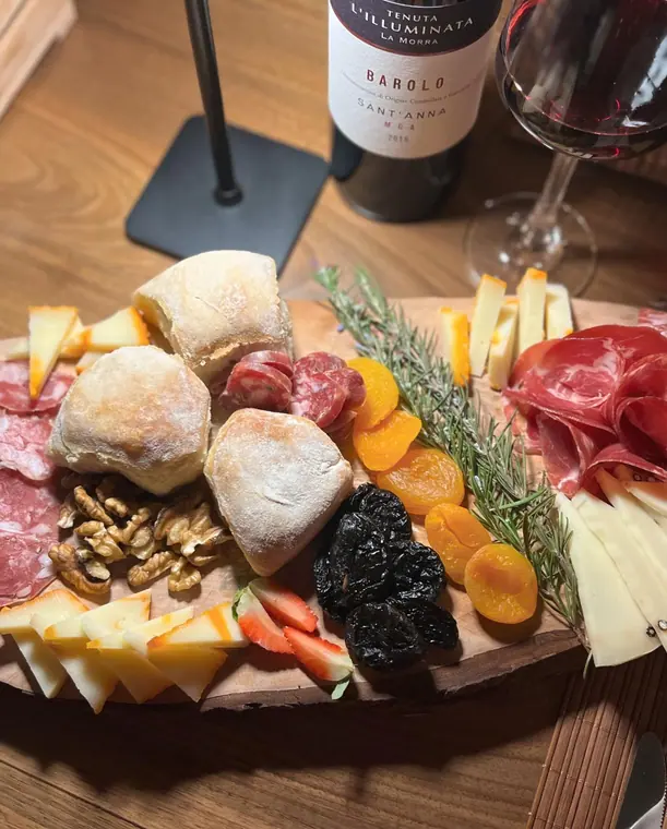 Cheese and cured meat board beside wine bottle and glass